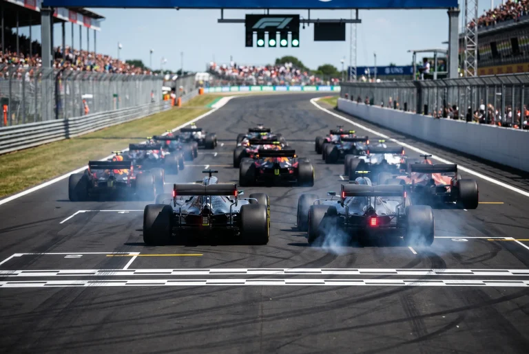 F1 cars accelerating off the starting grid at the start of a Sprint race with smoke from spinning tyres