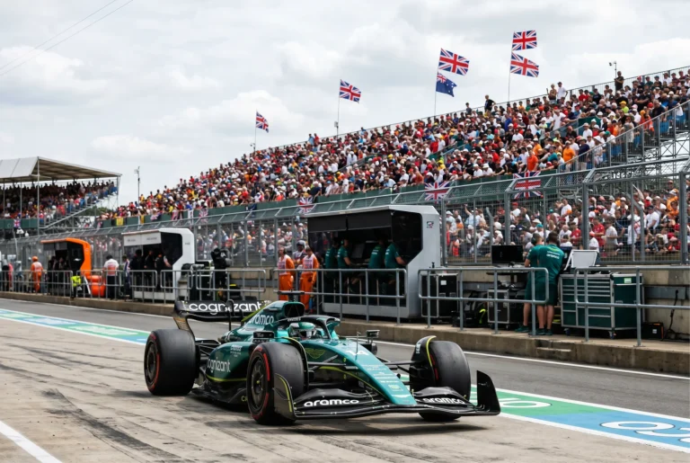 Formula 1 car on the pit lane at Silverstone with British grandstand crowds in the background